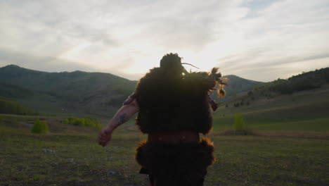 Man-in-ethnic-costume-runs-along-valley-to-distant-mountain