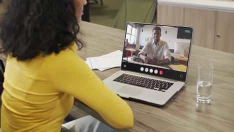 Mujer-Birracial-Usando-Una-Computadora-Portátil-Para-Videollamada,-Con-Un-Colega-De-Negocios-En-La-Pantalla