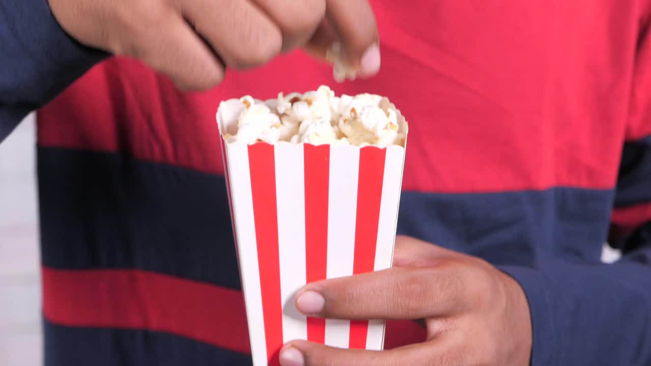 persona que sostiene una caja de palomitas de maíz