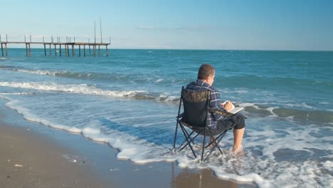 man reading book on the beach