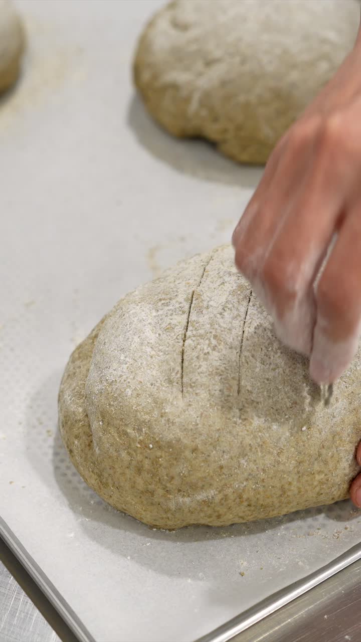 Baker's Hand Scoring Fresh Bread Dough with a Lame