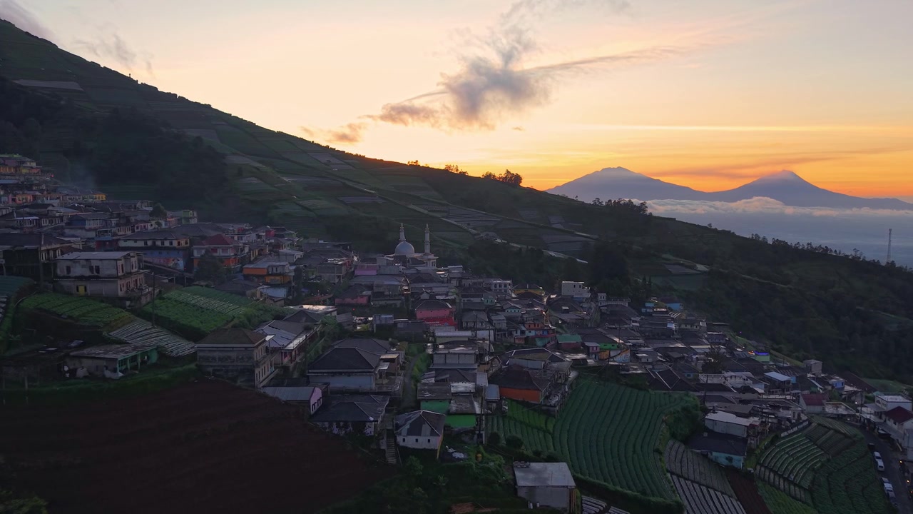 Vista drone mattutina di un villaggio collinare, caldi colori dell'alba su terreni agricoli e paesaggio montano. Nepal Van Java, Indonesia.