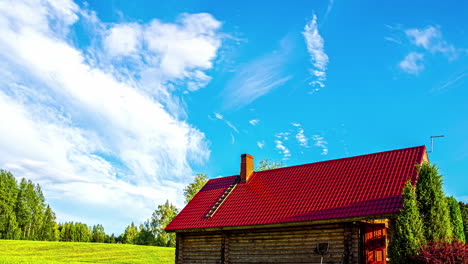 timelapse footage of moving clouds and a tiny cottage with red roof situated in a grass field