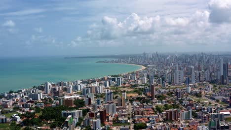 rising aerial wide shot of the tropical beach city of cabedelo, brazil from the intermares beach near joao pessoa with skyscrapers along the coastline in the state of paraiba on a summer day