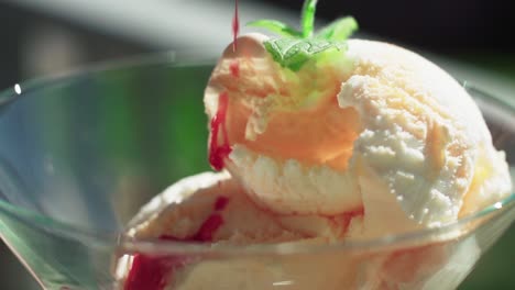 a shot of vanilla ice cream in a glass with a strawberry, red sauce poured on it in slow motion