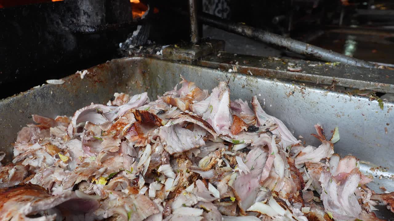 Al pastor meat sliced from spit and falling into container