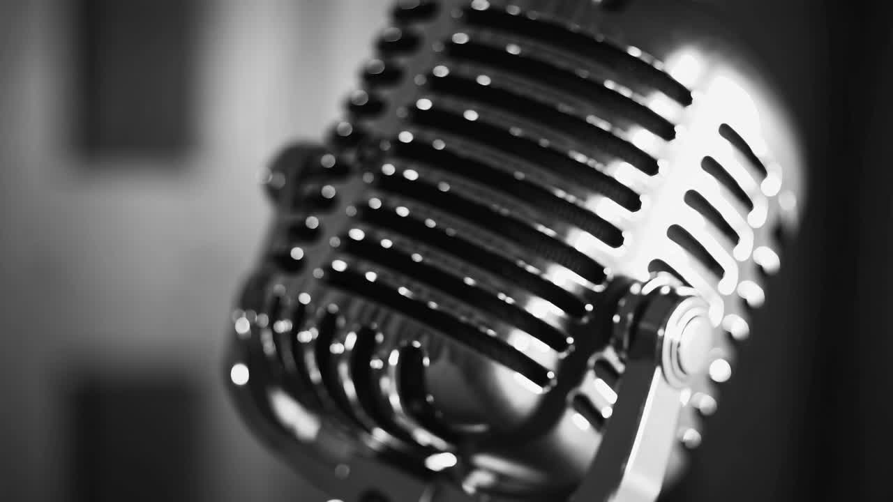 Close-up, black and white image of a vintage microphone, capturing its retro style and detail