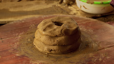 Close-up-footage-of-traditional-pottery-making-in-Asia,-showing-an-artisan-setting-up-clay-on-a-foot-powered-turning-table-for-a-new-vase