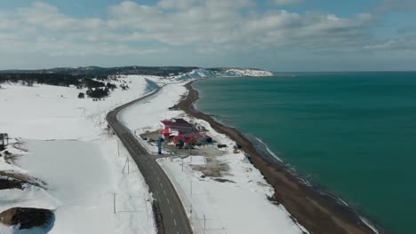 National Route 238 Along Snowy Coastline, Leading To Wakkanai In Hokkaido, Japan. wide aerial shot