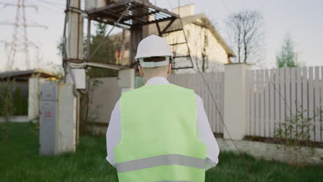 engineer in safety gear walking near power infrastructure