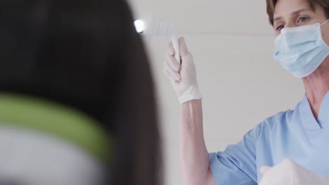 Caucasian-female-dentist-with-face-mask-preparing-female-patient-at-modern-dental-clinic