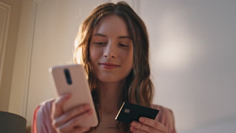 young woman entering credit details in sunlight closeup. smiling girl shopping