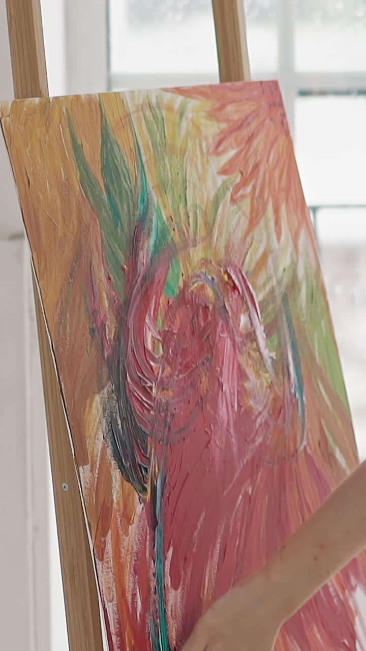Inspirited woman artist in white blouse applies paint on canvas by fingers drawing bright picture on wooden easel in studio slow motion close side view