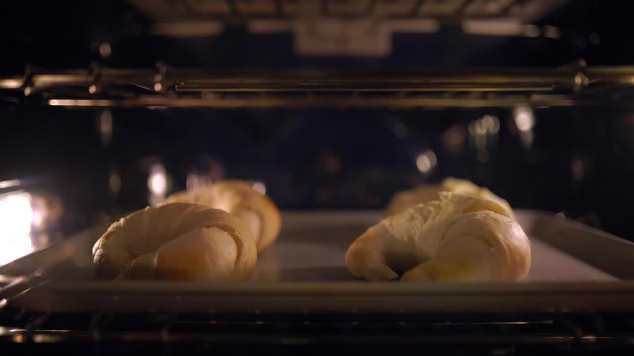 En time-lapse av 4 croissanter som stekes i en ovn, som viser deigen heve seg.