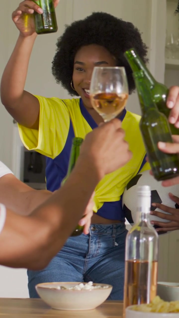 Vertical video: Cheering woman in white joining after man raising glass at kitchen, green bottles