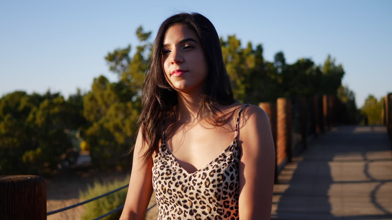 una hermosa modelo hispana jugando con una bola de cristal mágica en cámara lenta mientras sonríe y ríe alegremente al atardecer
