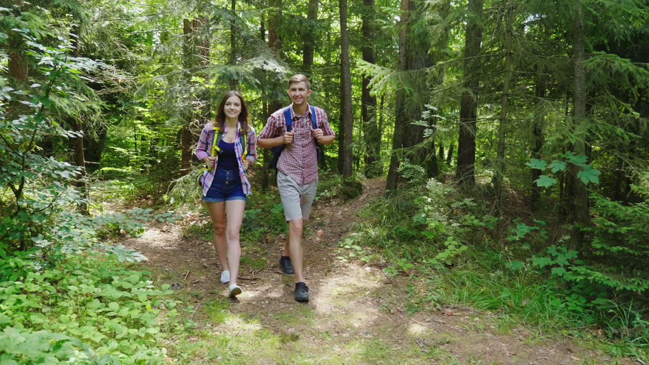 una pareja joven y atractiva está caminando por el bosque haciendo senderismo y un estilo de vida activo