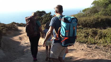 familia de excursionistas con mochilas caminando por el camino al aire libre