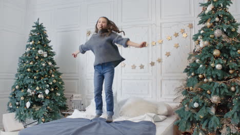 smiling teenage girl jumping bed in home. happy kid having party in bedroom