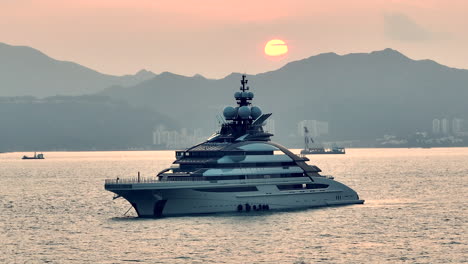 luxury private super yacht anchored in hong kong, sunset, cinematic aerial panning shot