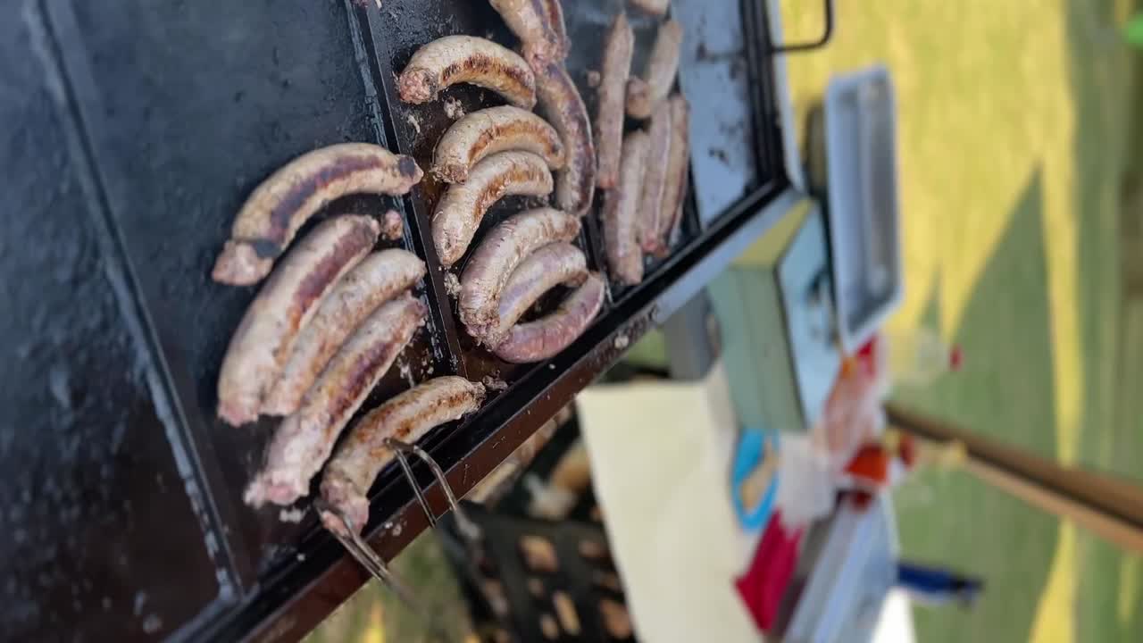 girando la barbacoa salchichas braai boerewors al aire libre en la parrilla de gas, braai chisporroteante