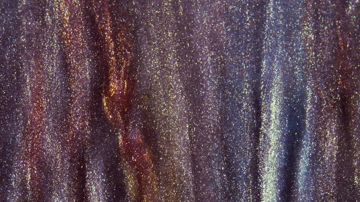 Golden ink particles flows in water as colorful chaos on the black background