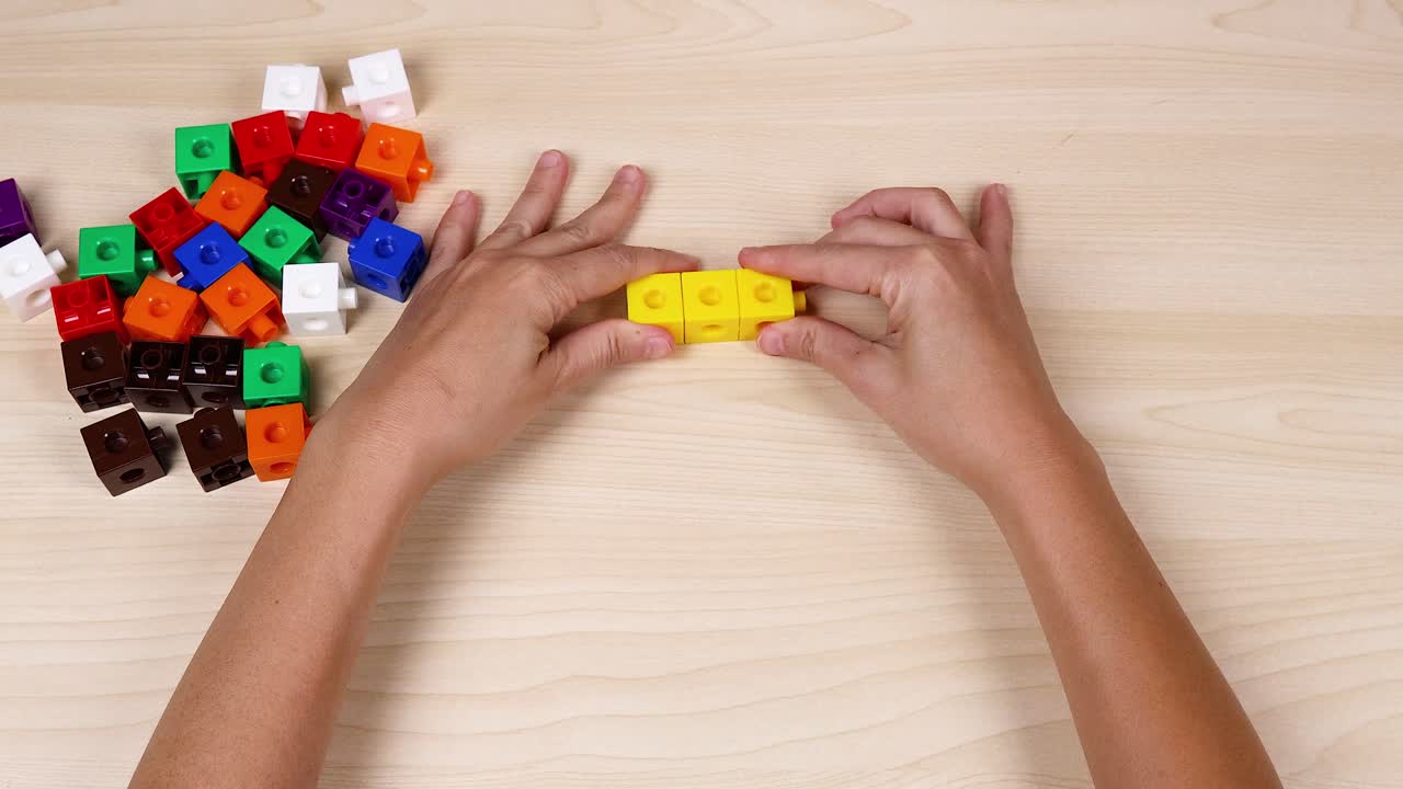 manos montando cubos amarillos en una mesa de madera