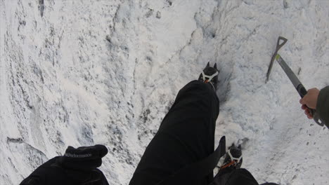 feet view of a mountain climber in the swiss alps on a steep glacier, with all the equipement: snowpick, rope and shoes