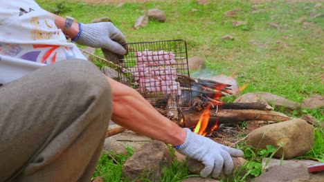 Nahaufnahme-Einer-Person,-Die-Einen-Grill-Mit-Essen-Zum-Kochen-über-Ein-Lagerfeuer-Bewegt