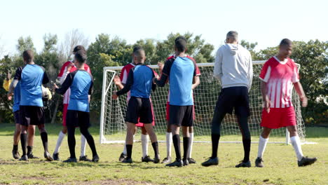 soccer players in uniforms gathering on field, preparing for match