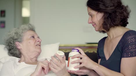 Daughter-showing-pills-bottles-to-mother,-explaining-difference