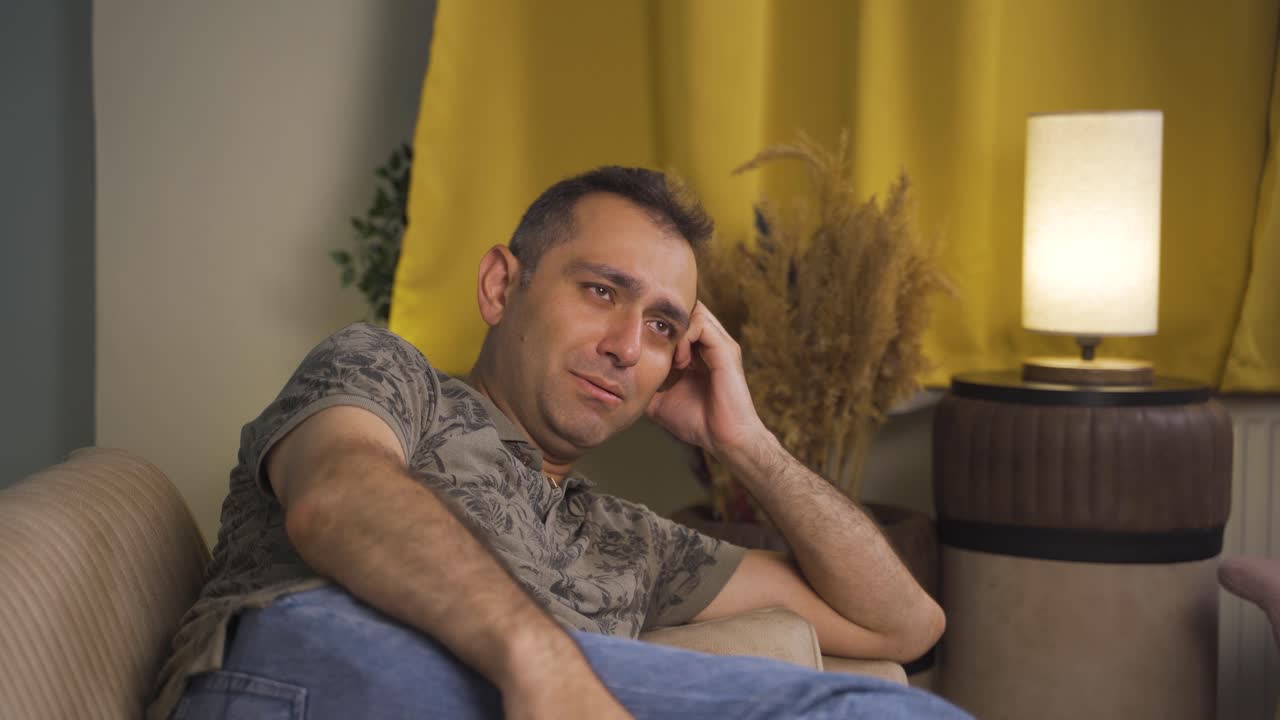 el hombre acostado en el sofá está llorando.