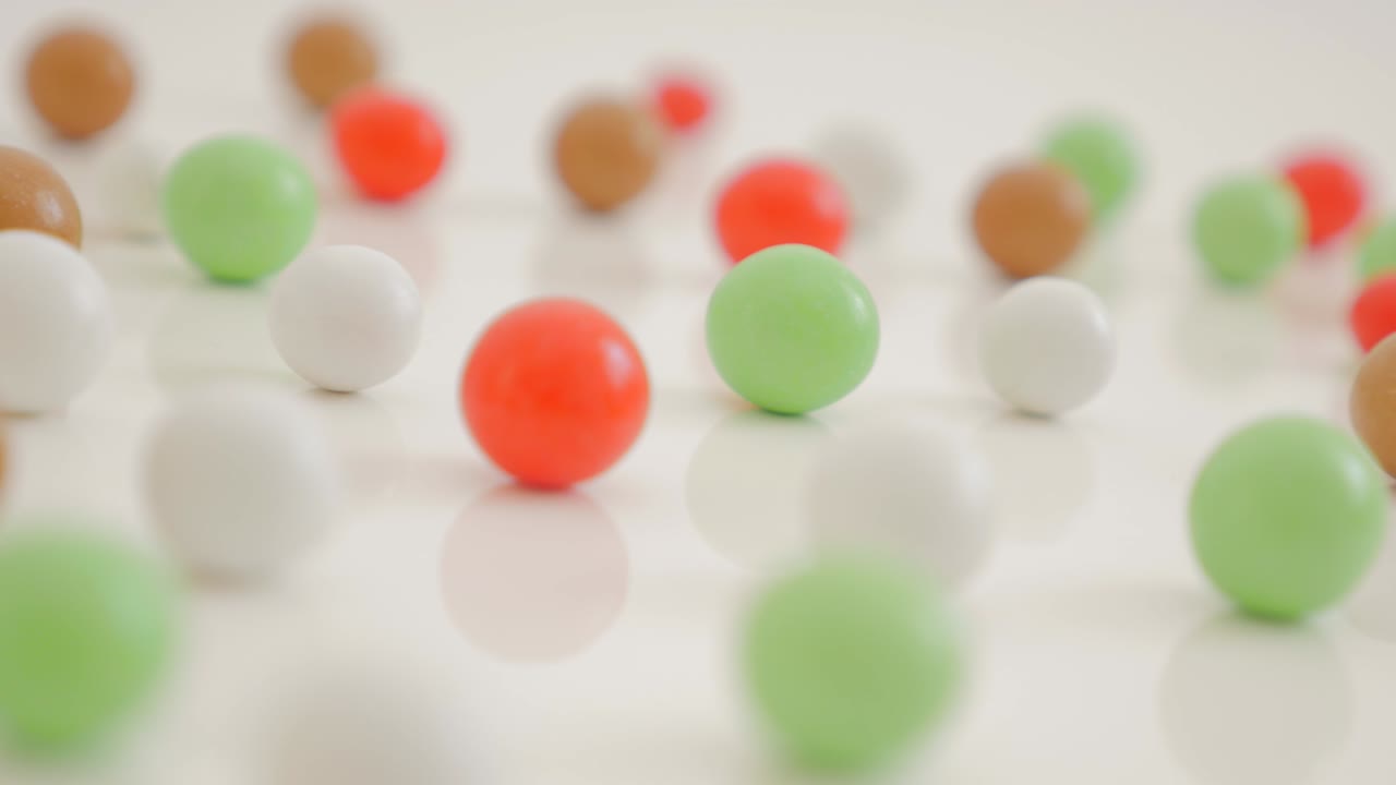 caramelos redondos y coloridos en superficie reflectante blanca 4k