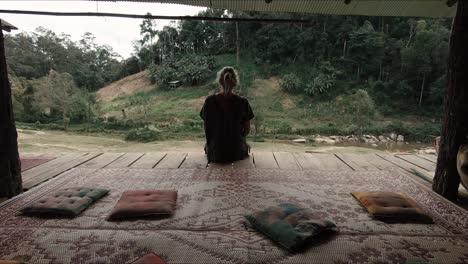 female tourist sitting on a wooden platform overlooking a jungle valley