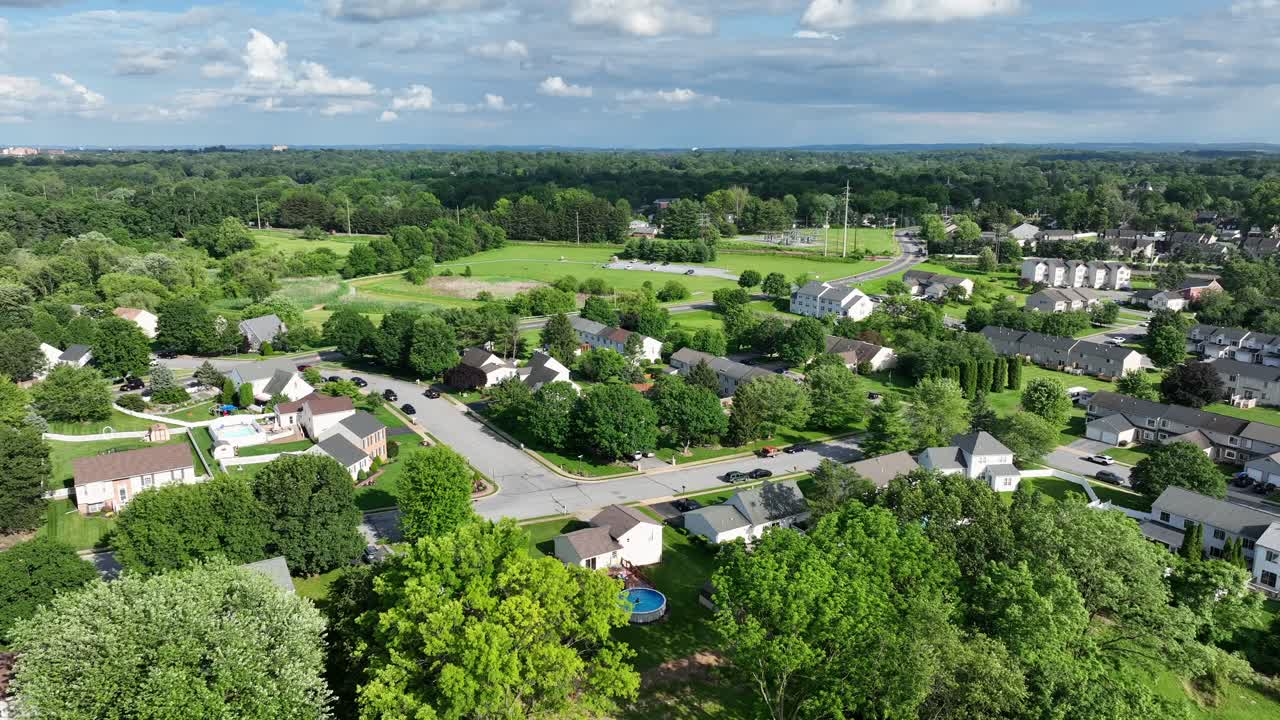 Veduta aerea di Lancaster, Pennsylvania, in estate. Vegetazione lussureggiante e case suburbane si estendono sul paesaggio sotto un cielo azzurro. Una comunità pacifica e vivace con spazi aperti e un fascino paesaggistico