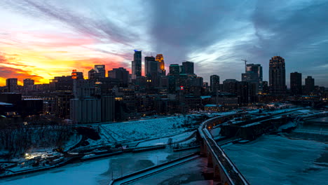 aerial hyperlapse of the sun setting behind the minneapolis skyline with snow covering the ground