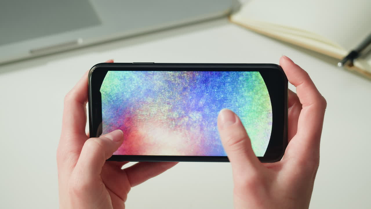 Person holding a smartphone with a colorful display.