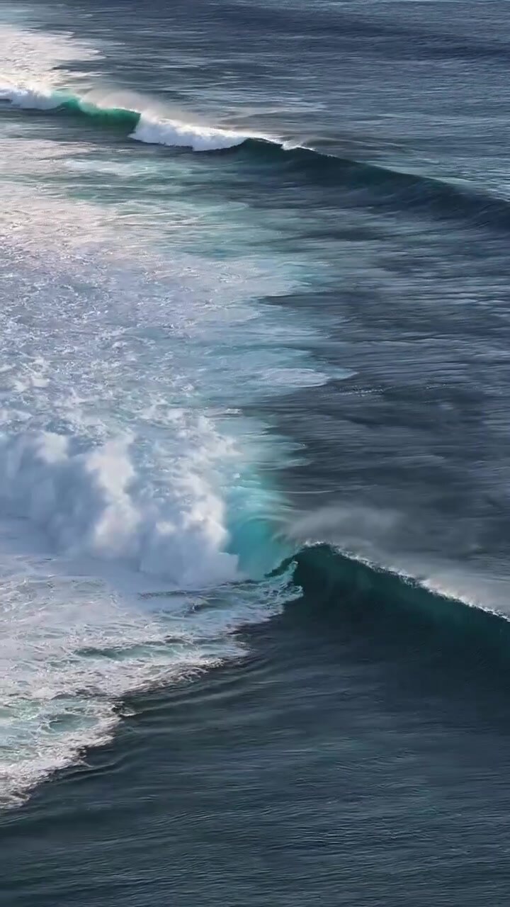 Powerful blue waves move energetically across the open sea, creating dynamic patterns. Suitable for marine-themed projects or as an energetic background.