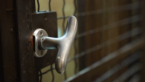 a person opens the door handle of the old vintage elevator, enters the lift and descends