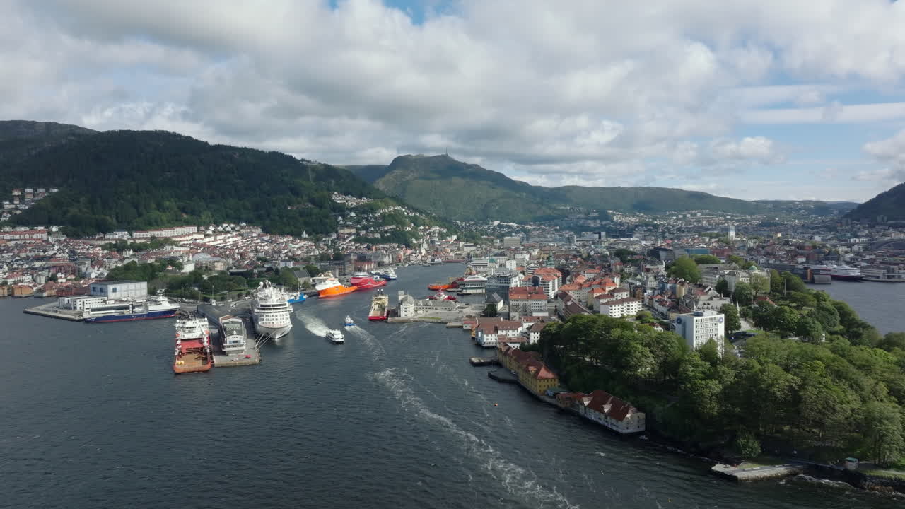 Aerial approach toward Bergen city center, showcasing the waterfront, mountains and traditional architecture