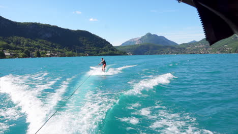 wide shot of wakesurfer riding the waves with mountain range in the background