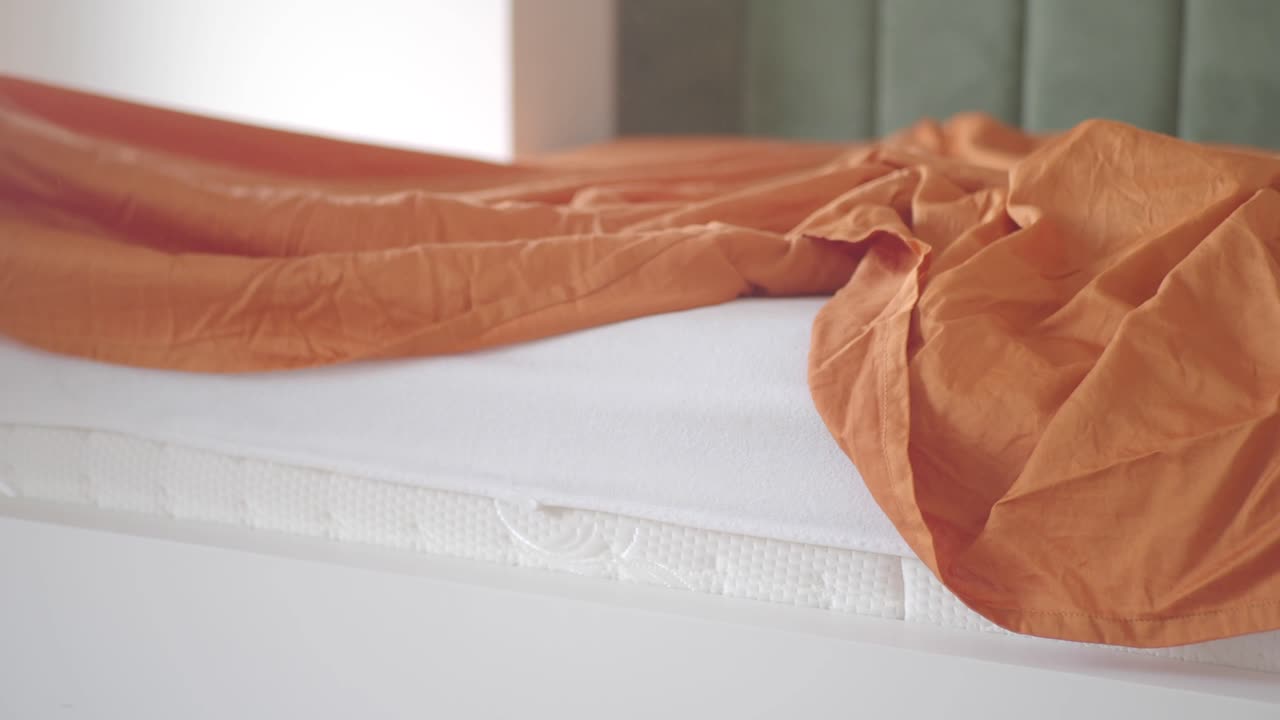 오렌지색 침대 시트와 함께 만들어지지 않은 침대