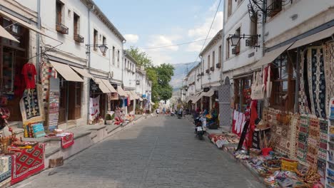 Old-bazarr-on-stone-and-brick-roadways,-lined-with-sconces-and-a-backdrop-of-the-Gjere-mountains-in-Gjirokaster,-Albania