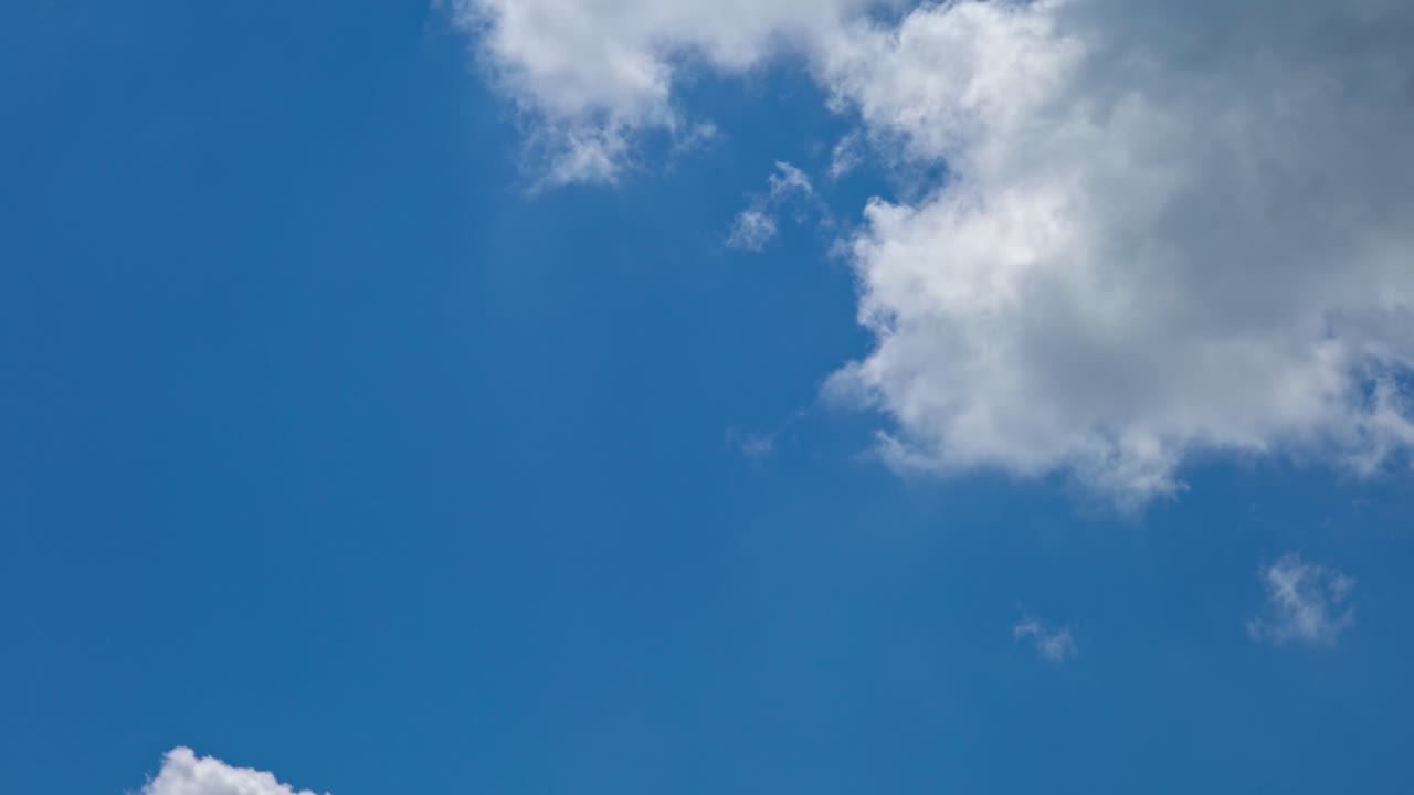 Clouds float in the blue sky during a sunny day above the horizon