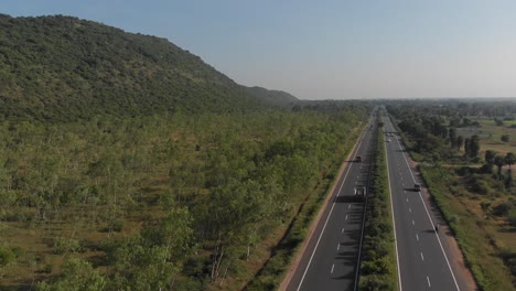 Schöne-Aufnahme-Von-Autos-Und-Lastwagen,-Die-In-Einer-Ländlichen-Gegend-Indiens-Eine-Autobahn-Hinunterfahren