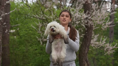 una adolescente con un perro maltés en un parque de primavera