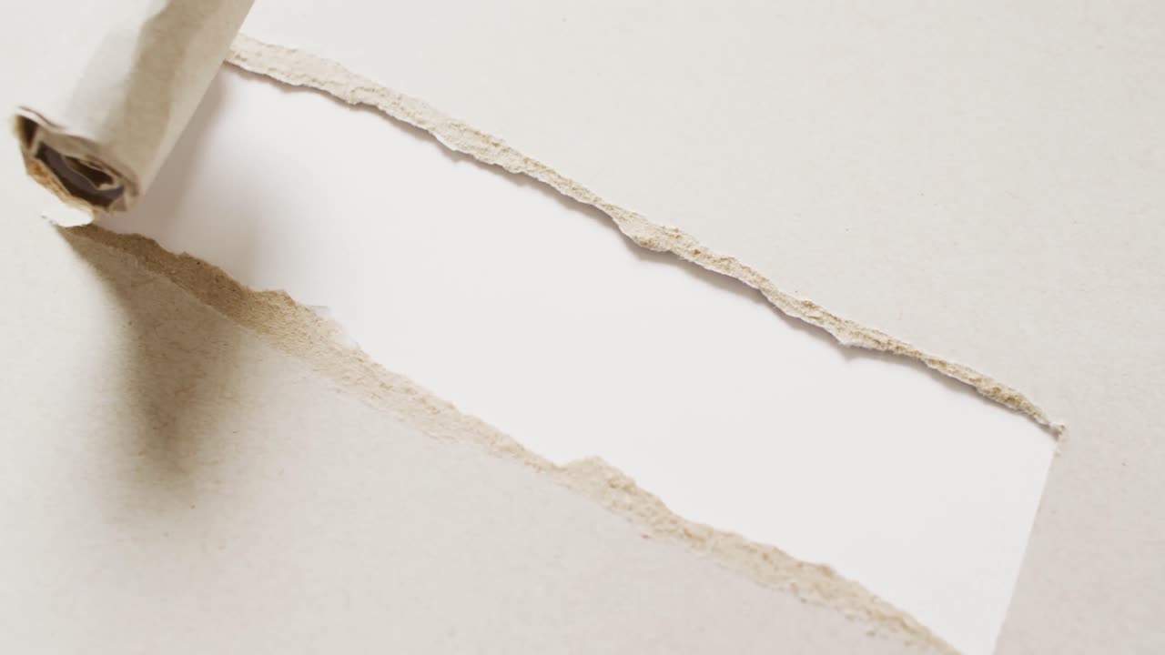 video de primer plano de un pedazo de papel beige roto sobre un fondo blanco