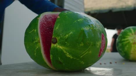 African-American-man-slicing-large-green-juicy-watermelon-in-half-at-campground-for-bbq