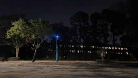 panning view, blue light on emergency phone station in parking lot