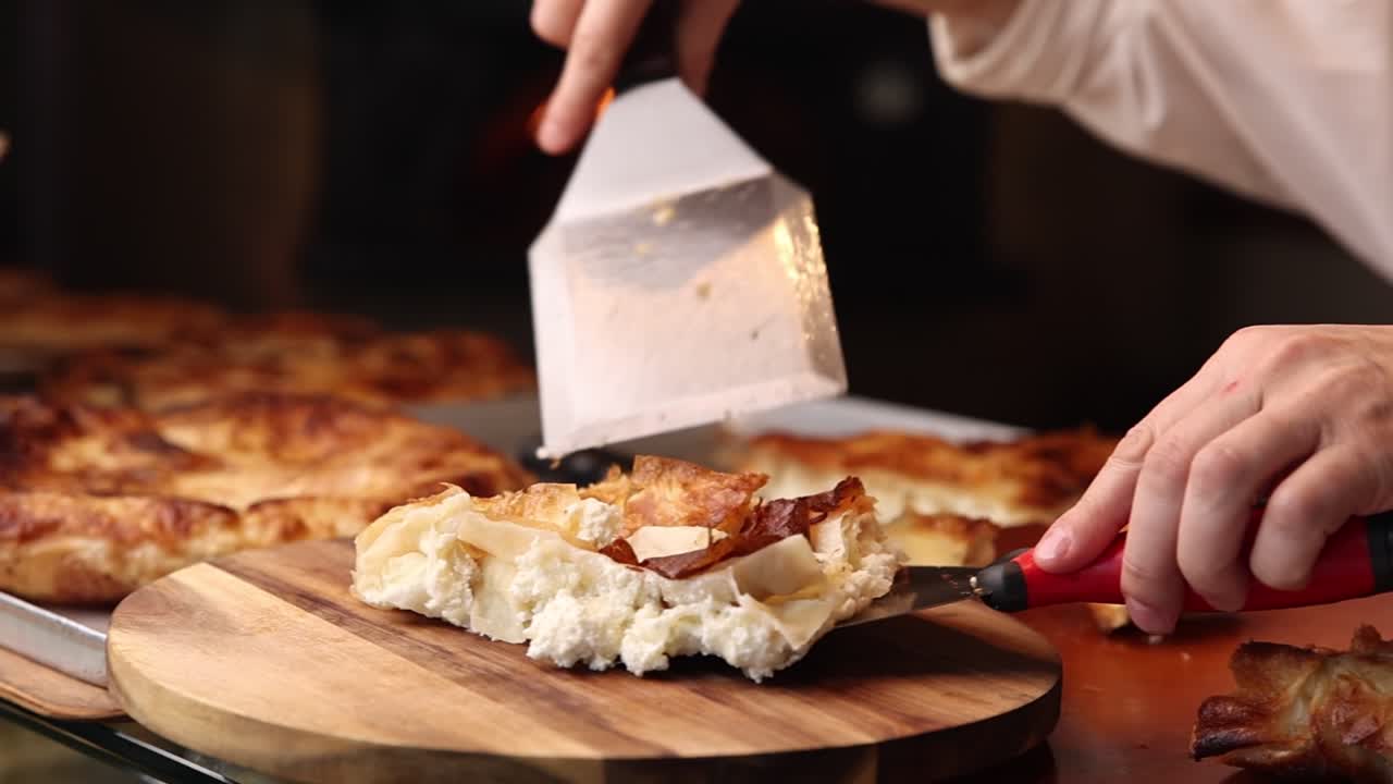 Chef che taglia una fetta di Burek al formaggio appena sfornato